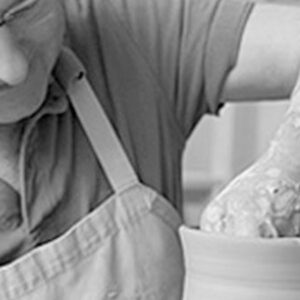 Un ceramista profesional trabaja en su torno, dando forma a una de sus creaciones en cerámica.