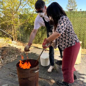 Un hombre y una mujer cocen cuidadosamente piezas de arcilla en un horno para barro y cerámica de forma ancestral