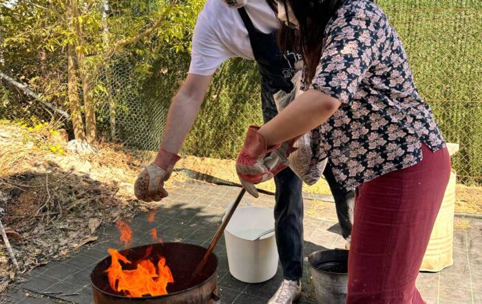 Un hombre y una mujer cocen cuidadosamente piezas de arcilla en un horno para barro y cerámica de forma ancestral