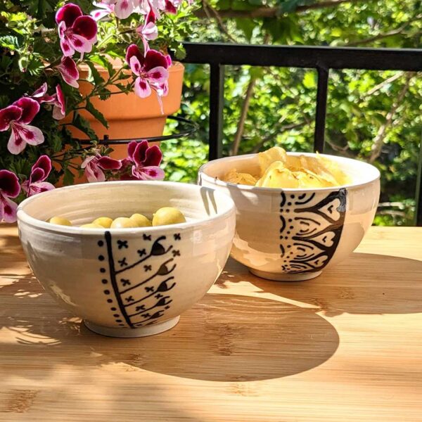 Tazas de barro decoradas pequeñas con comida sobre una mesa en un fondo natural