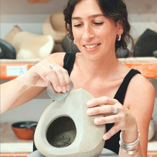 Una mujer sonriente trabaja creando formas con arcilla blanca