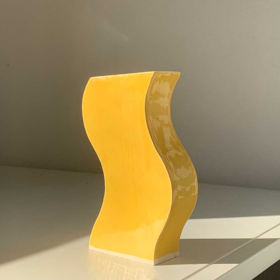 Jarrón de diseño en cerámica de color amarillo sobre una mesa