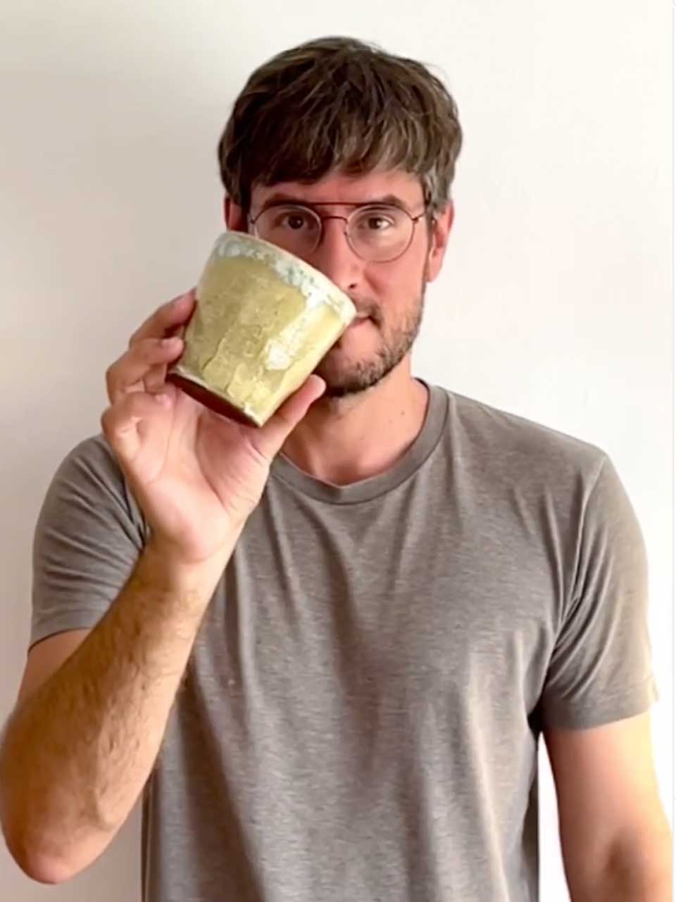 Hombre con gafas mira a la cámara sosteniendo una taza cerámica sin asa